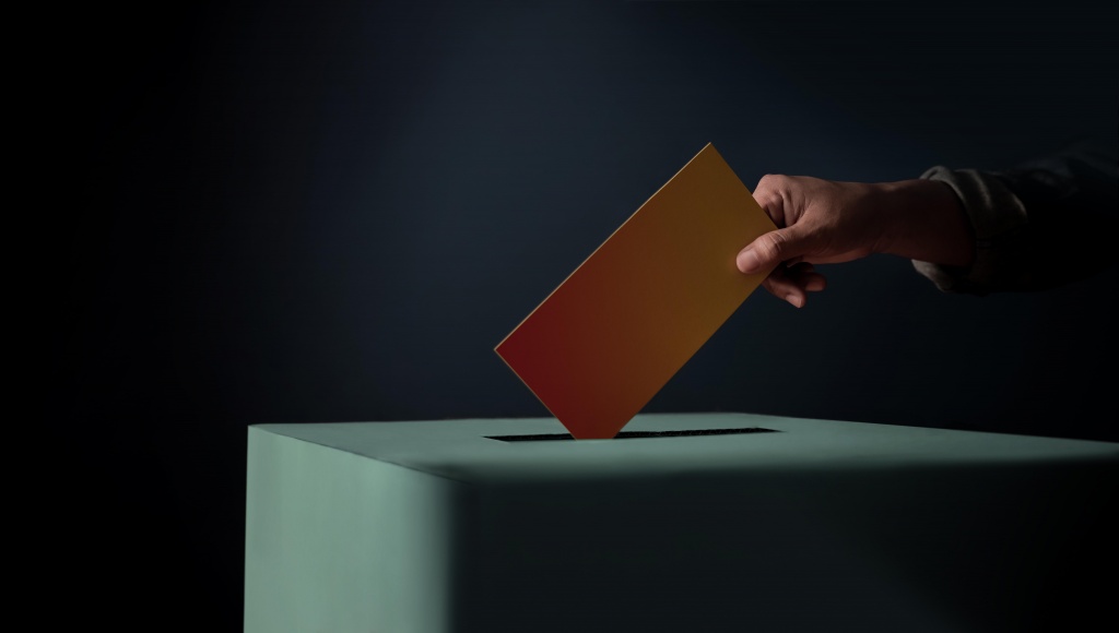 1627562031_election-concept-person-dropping-ballot-card-into-vote-box-dark-cinematic-tone